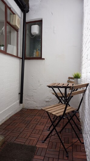 Enjoy a quiet moment in this serene outdoor space with a table for four and a lush potted plant.