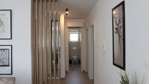 En hall med trägolv, ett matområde med ett bord och stolar samt inramade konstverk på väggarna.