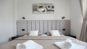 Ett modernt hotellrum med en stor säng, två sängbord, en sänggavel och ett konstverk på väggen.