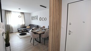 Ett modernt vardagsrum med en matplats, en grå soffa, ett soffbord och ett matbord med plats för fyra personer.