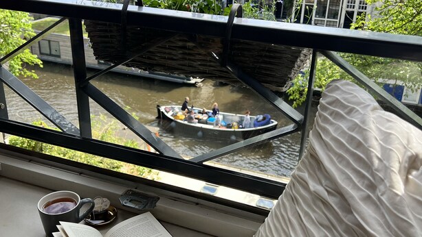 A view from a window overlooking a canal with a boat, a balcony with a book, and a cup of tea. - Apartment overlooking the beautiful Brouwersgracht canal in Amsterdam centre (Amsterdam)