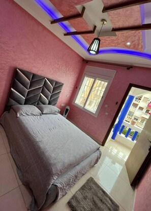 A bedroom with a bed, a ceiling light, a window, and a view of the outside.