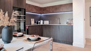 Une cuisine moderne avec des meubles de couleur bois foncé, un four encastré et un plan de travail élégant.