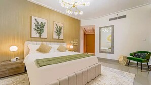 A modern bedroom with a large bed, a chandelier, and a green armchair.