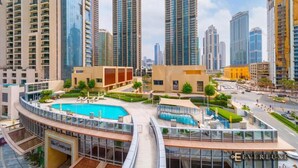 A modern high-rise building with a central courtyard featuring a swimming pool and outdoor seating areas.