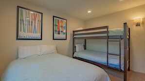 Une chambre avec des lits superposés, un grand lit et deux affiches encadrées au mur.