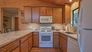Une cuisine avec des meubles de rangement en bois, une cuisinière blanche, un four à micro-ondes et un évier.