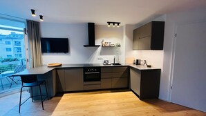 Une cuisine moderne dotée d’un îlot central, d’appareils électroménagers intégrés et offrant une vue sur la ville grâce à de grandes fenêtres.