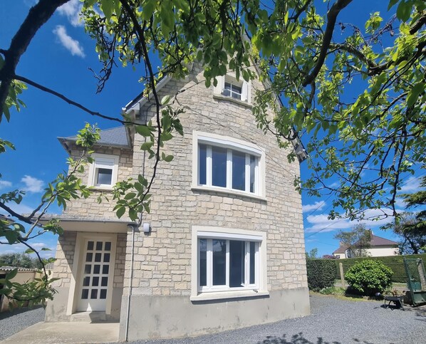 A two-story stone building with a beige facade, white-framed windows, and a small porch area.