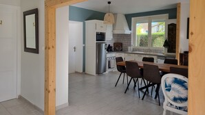 Eine moderne Küche mit weißen Schränken, einem Edelstahlkühlschrank und einem Essbereich mit Holztisch und Stühlen.