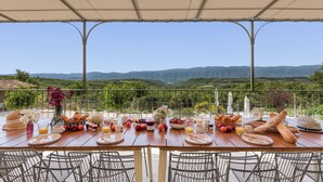 Mesa para el desayuno al aire libre con vistas panorámicas a colinas y un porche cubierto.