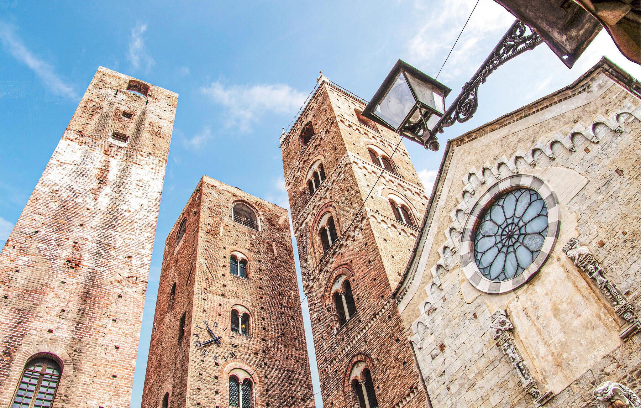 A historic building with tall brick towers and a large circular window with intricate stonework.