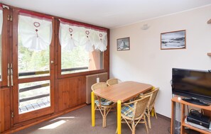 A cozy room with a wooden table and chairs, a television, and framed pictures on the wall. - Gorgeous apartment in Breuil-Cervinia with WiFi (Breuil-Cervinia)