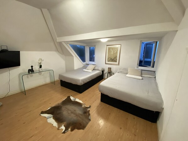 Relax in this serene bedroom with a large central bed, two smaller beds, and a flat-screen TV.