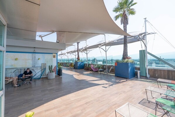 Une terrasse extérieure aménagée avec des sièges, des plantes et une vue sur la ville.