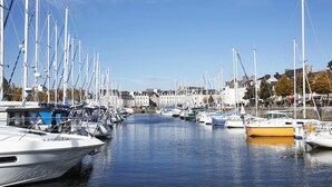 A marina with multiple boats docked along a calm waterway, surrounded by buildings and trees. - A Deux Pas du Port - Vannes (VANNES)