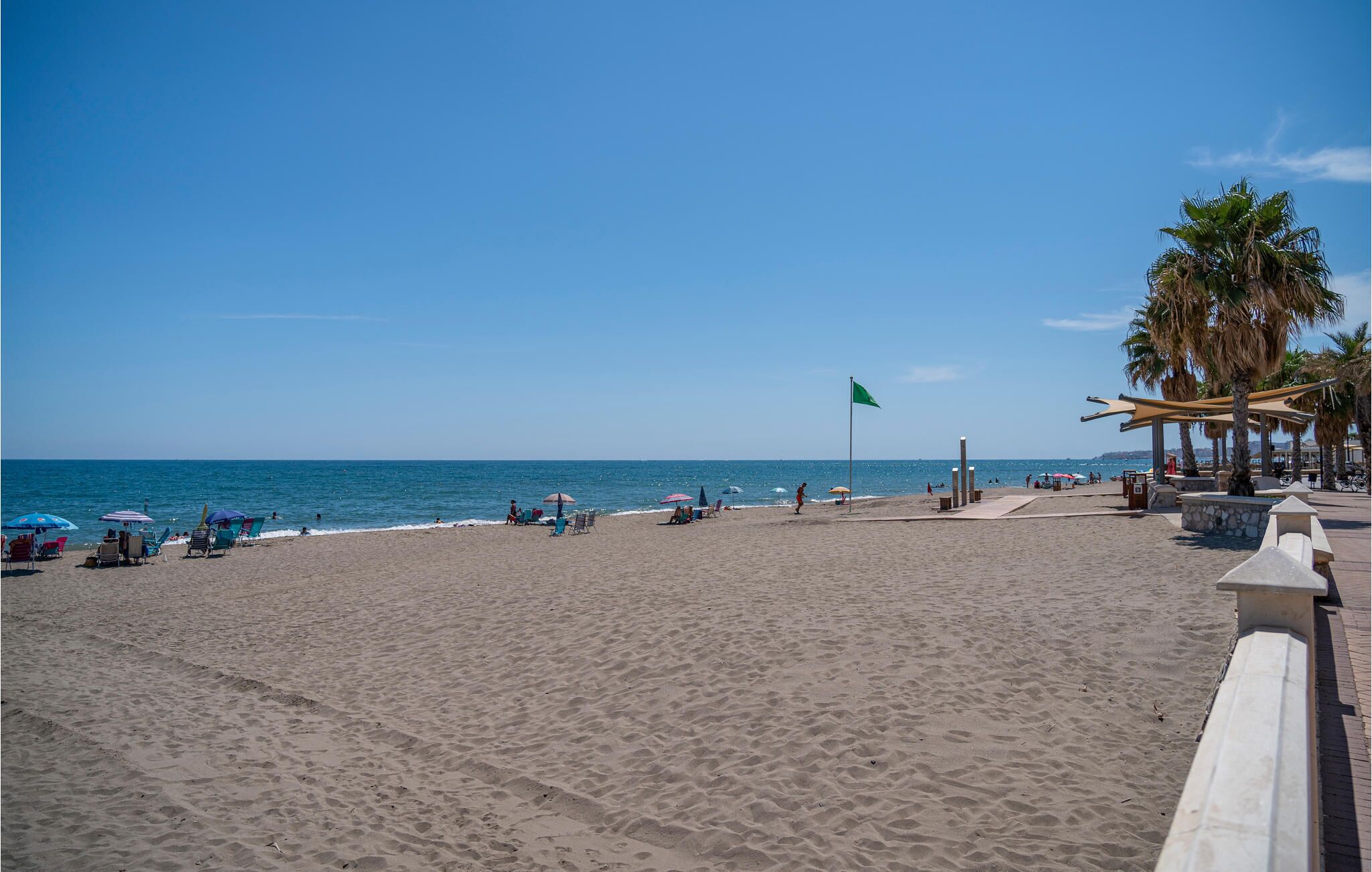 Une plage avec un drapeau, des palmiers et des chaises de plage.