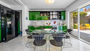 A modern kitchen with green cabinets, a glass dining table, and four chairs. - 4 bedroom amazing home in Zaboric (Zaboric)