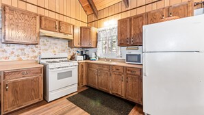Una cocina con armarios de madera, estufa, refrigerador y microondas.