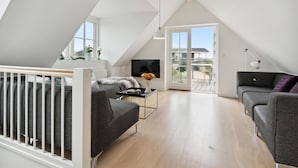 En modern lägenhet i loftstil med högt i tak, stora fönster och en balkong.