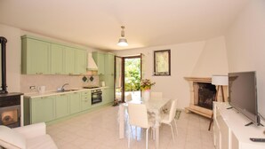 A modern kitchen with green cabinets, a dining area with a white table and chairs, and a fireplace. - 2 bedroom cozy home in Vasanello (Vasanello)