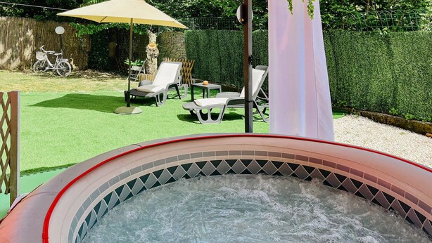 A hot tub with a tiled interior, surrounded by a grassy area with lounge chairs and a bicycle. - 2 bedroom cozy home in Vasanello (Vasanello)