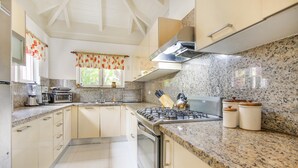 Eine Küche mit Granit Arbeitsplatten, einem Gasherd, einem Backofen und weißen Schränken.