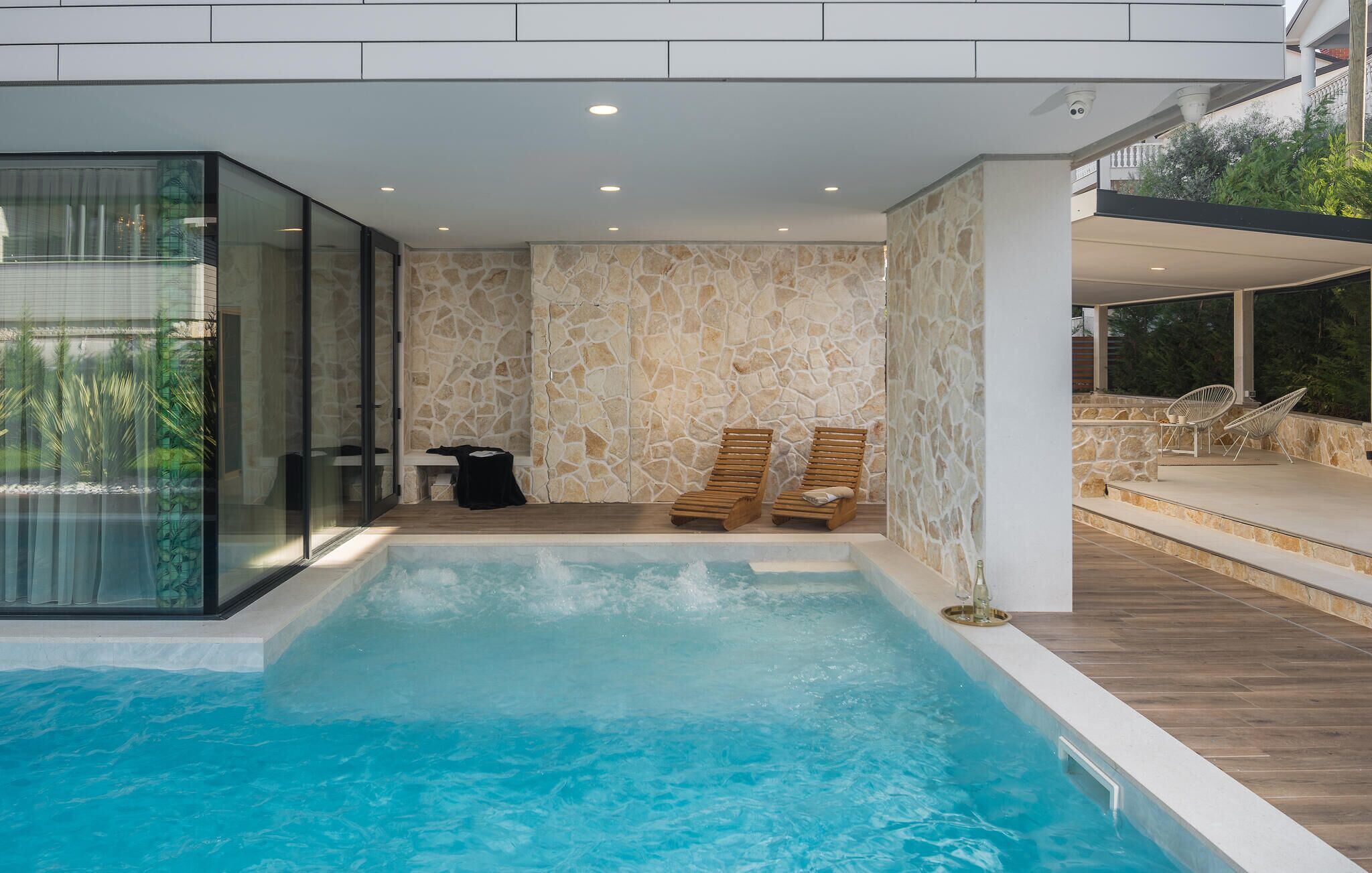 Ein moderner, überdachter Pool mit Steinwänden und Holzliegen.