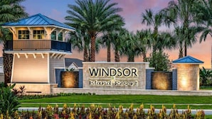 A resort sign with the name "Windsor Island Resort" and a building with a blue roof and balcony.