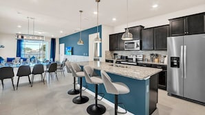 A modern kitchen with dark cabinets, stainless steel appliances, and a central island with bar stools.