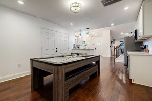 Uma cozinha moderna com armários brancos, mesa de bilhar de madeira e área de jantar com bancos.