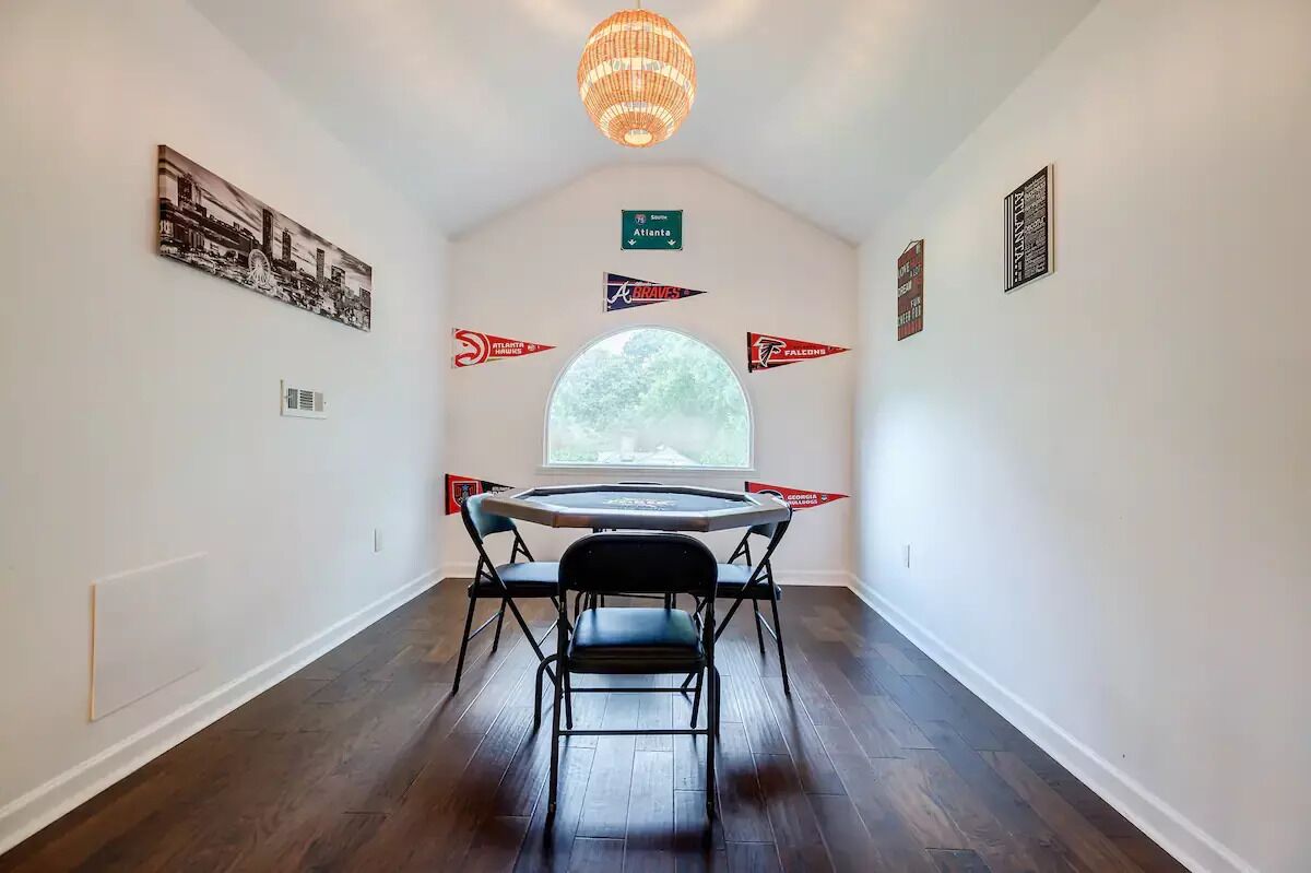 A narrow hallway with a round table and chairs, a large window, and Atlanta Braves memorabilia on the walls.