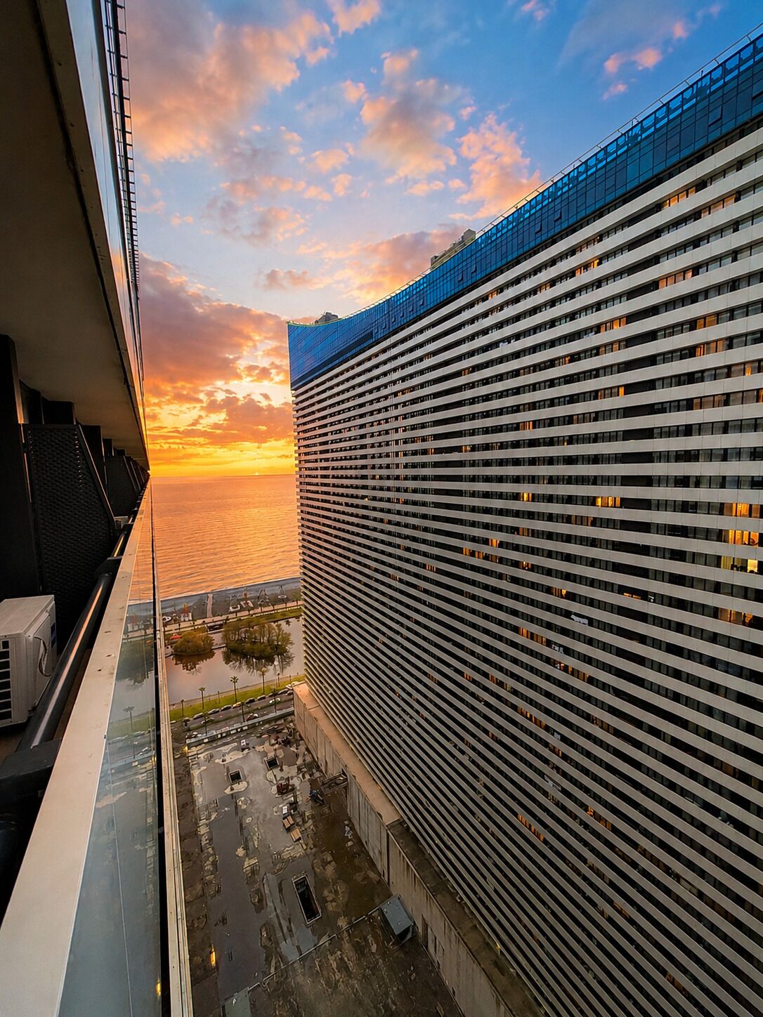 A high-rise building with a view of the sunset over the water.