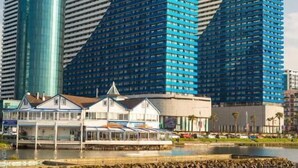 Een modern hoog gebouw met een opvallend hoekig ontwerp, gekenmerkt door een blauwe gevel en een cilindervormige constructie aan de linkerzijde.