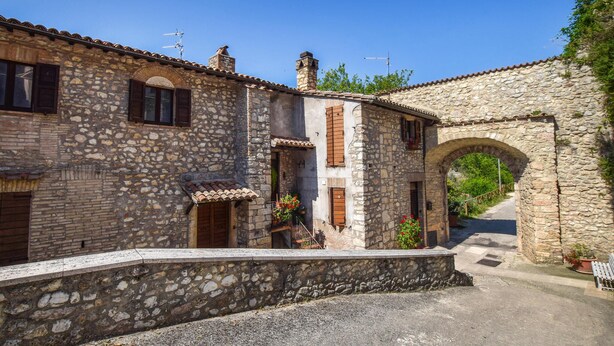 A stone building with a tiled roof, a wooden door, and a small balcony with potted plants. - Pet friendly apartment in Portaria (Portaria)