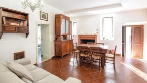A spacious living area with a fireplace, a dining table with chairs, a sofa, and a wooden cabinet. - Pet friendly apartment in Portaria (Portaria)