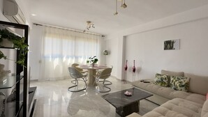 Un salon moderne comprenant un canapé, une table basse et un coin repas avec des chaises et une table.