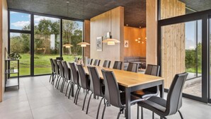 A modern dining area with a long table and chairs, large windows, and a view of the outdoors. - Lovely home in Højslev with sauna (Højslev)