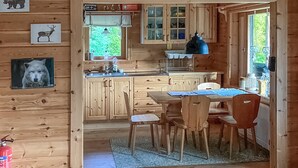 Una cocina estilo cabaña con armarios de madera, una mesa de comedor con sillas, una lámpara colgante azul y un extintor.