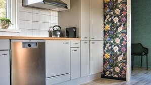 Et moderne køkken med opvaskemaskine, elkedel og kaffemaskine på bordpladen.