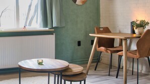 Et hyggeligt spiseområde med et rundt bord, stole, en radiator og et vindue med gardiner.