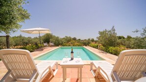 Ein Poolbereich mit Tisch, zwei Stühlen und einer Weinflasche.