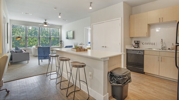 Een moderne keuken met een centraal eiland, barstoelen en een koffiehoek.