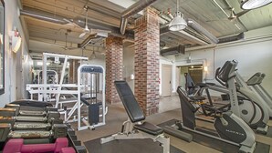 Een fitnessruimte met diverse trainingsapparaten, waaronder loopbanden, gewichten en krachtapparatuur.