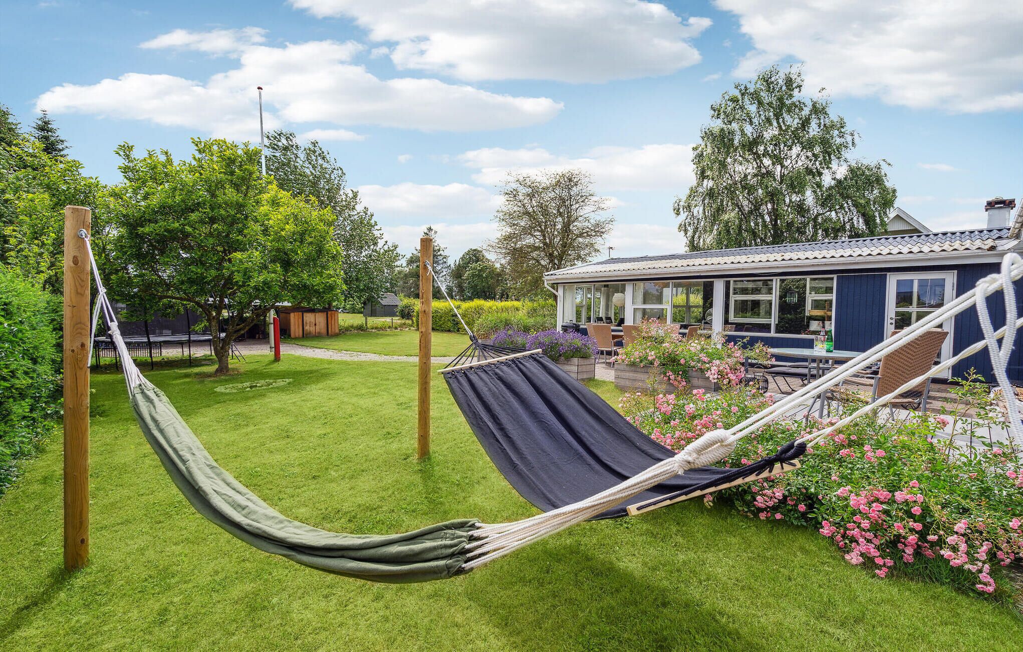 A hammock in a grassy garden with a house in the background.