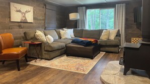 A cozy living room with a sectional sofa, a leather armchair, a patterned rug, and a fireplace. - Minutes to town or very peaceful woods retreat! Close to trails and golf. (Lewiston)