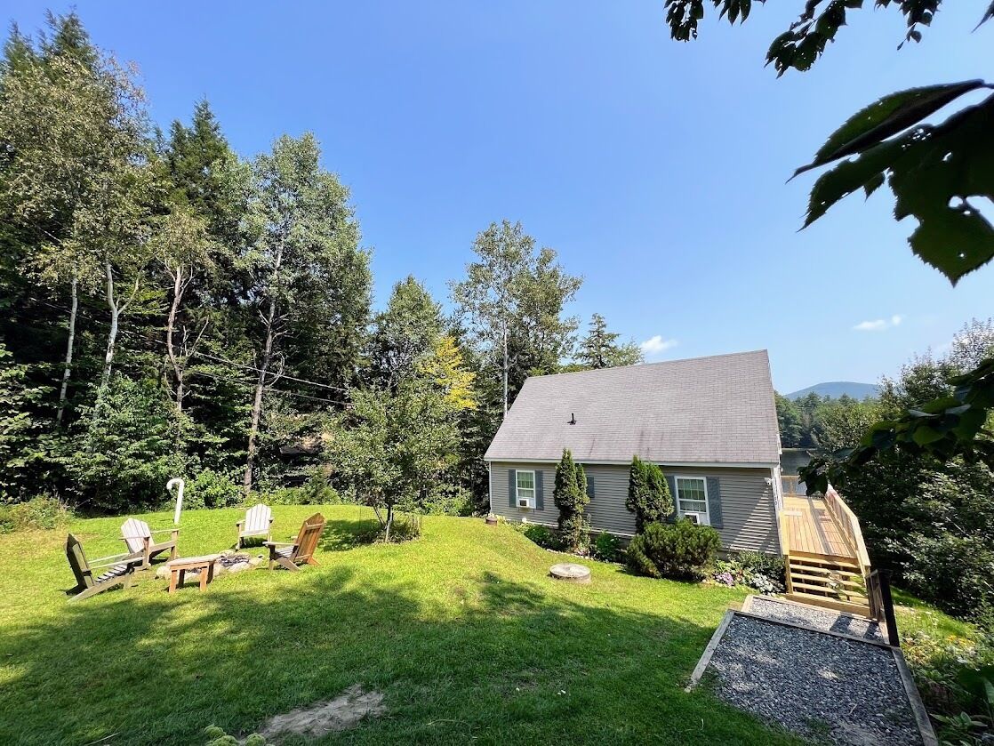 A house with a lawn, outdoor seating, and a wooden deck.