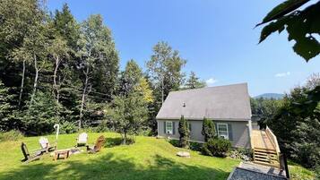 A house with a lawn, outdoor seating, and a wooden deck.