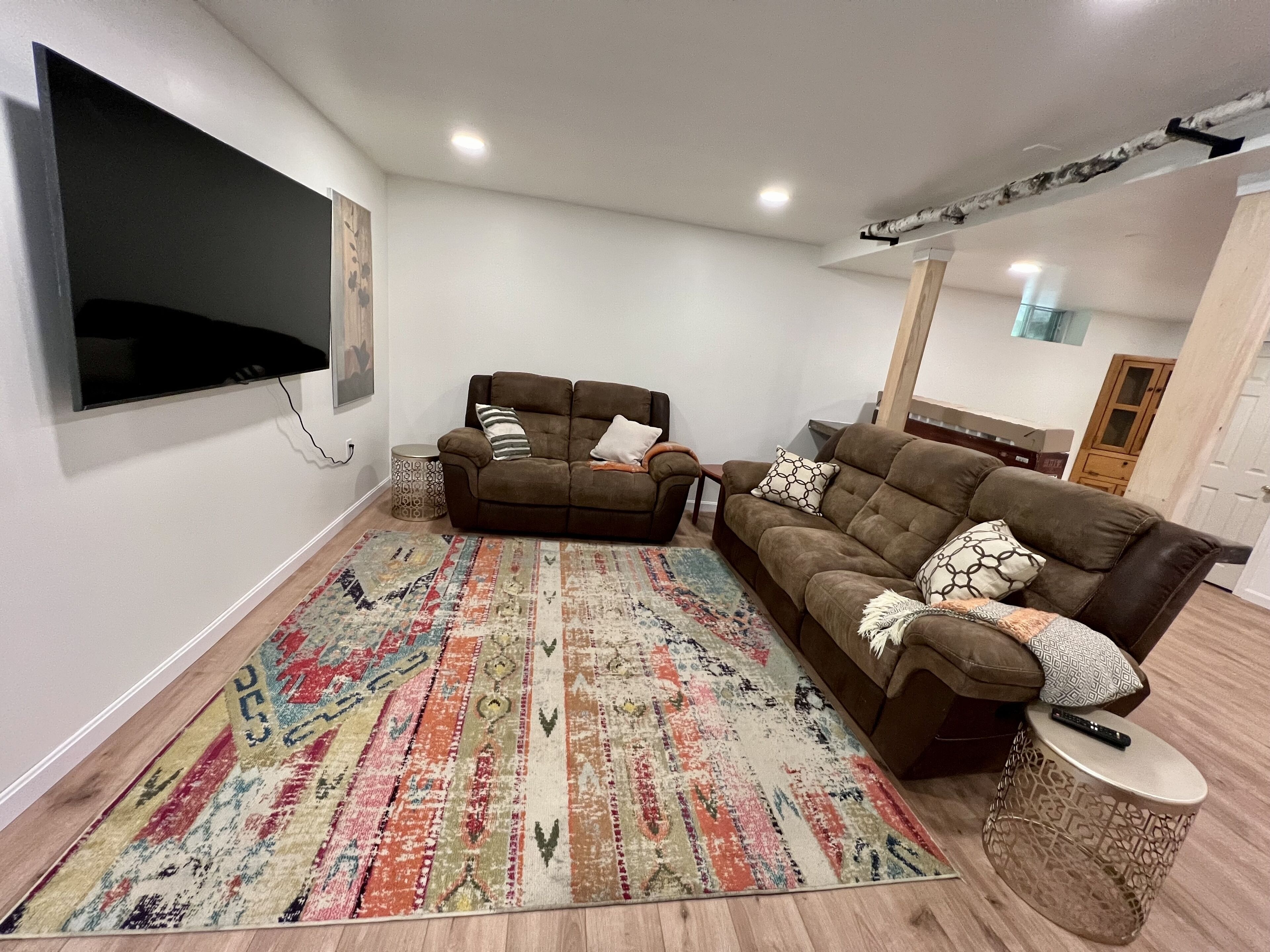 Un salon avec deux canapés, un téléviseur, un tapis à motifs et un meuble en bois.