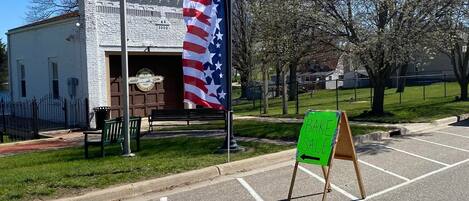 A parking lot with a green signboard, a white building, and a flagpole with an American flag.